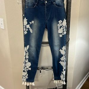 White embroidered jeans with tassels at the bottom.
